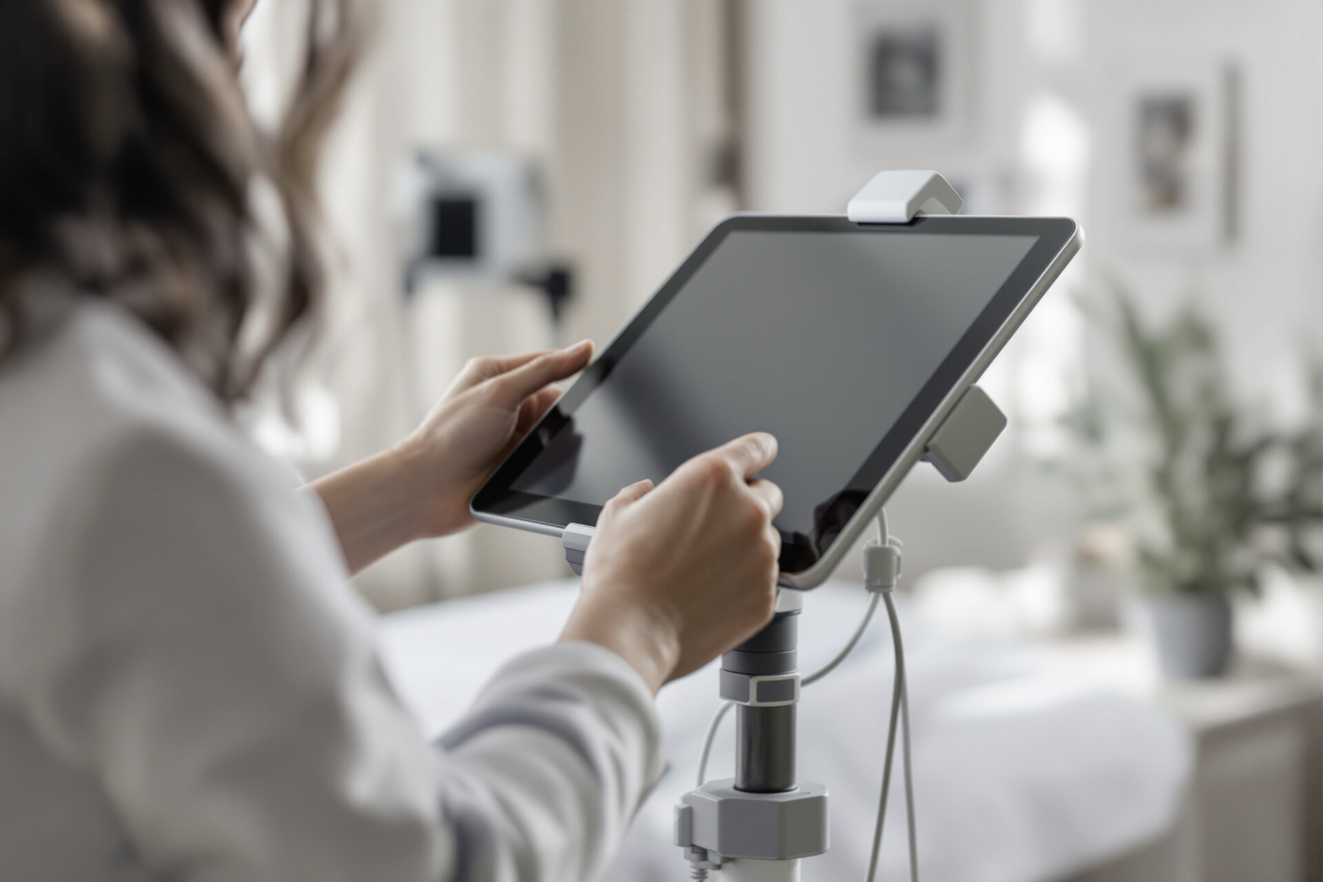 A clinician's hands adjusting a tablet in a treatment room.