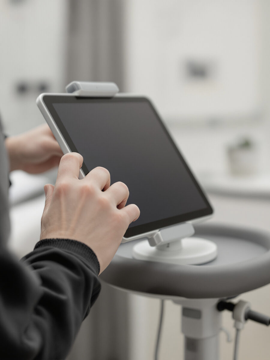 A clinician's hands adjusting a tablet in a treatment room.